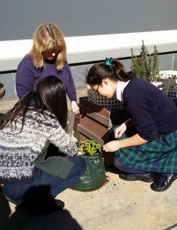 Ms. Pomroy and students planting vegetables 