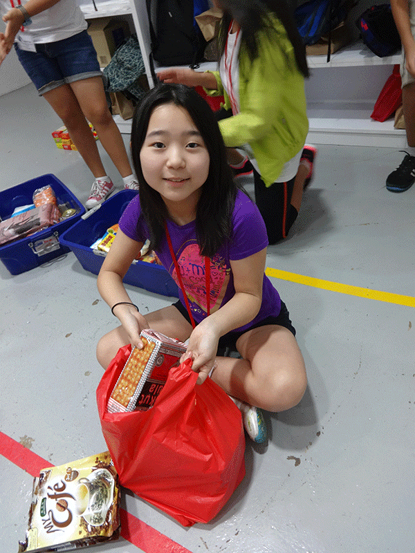 Risa (6) packs basic food items for a food bank in Singapore. 
