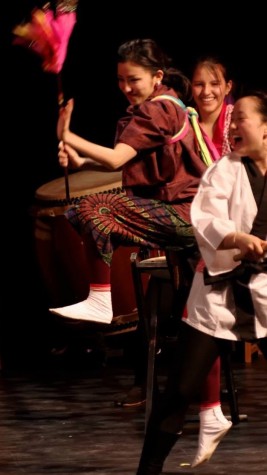 Eva smiles as she plays the Japanese drum while dancing for the audience.