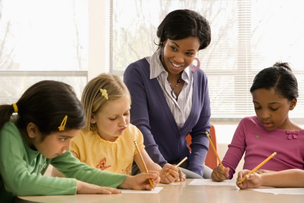 Teacher Helping Students by Depositphotos