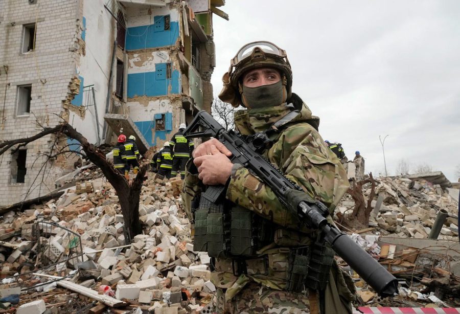 A Ukrainian soldier standing in front of an apartment ruined by Russian attack. 