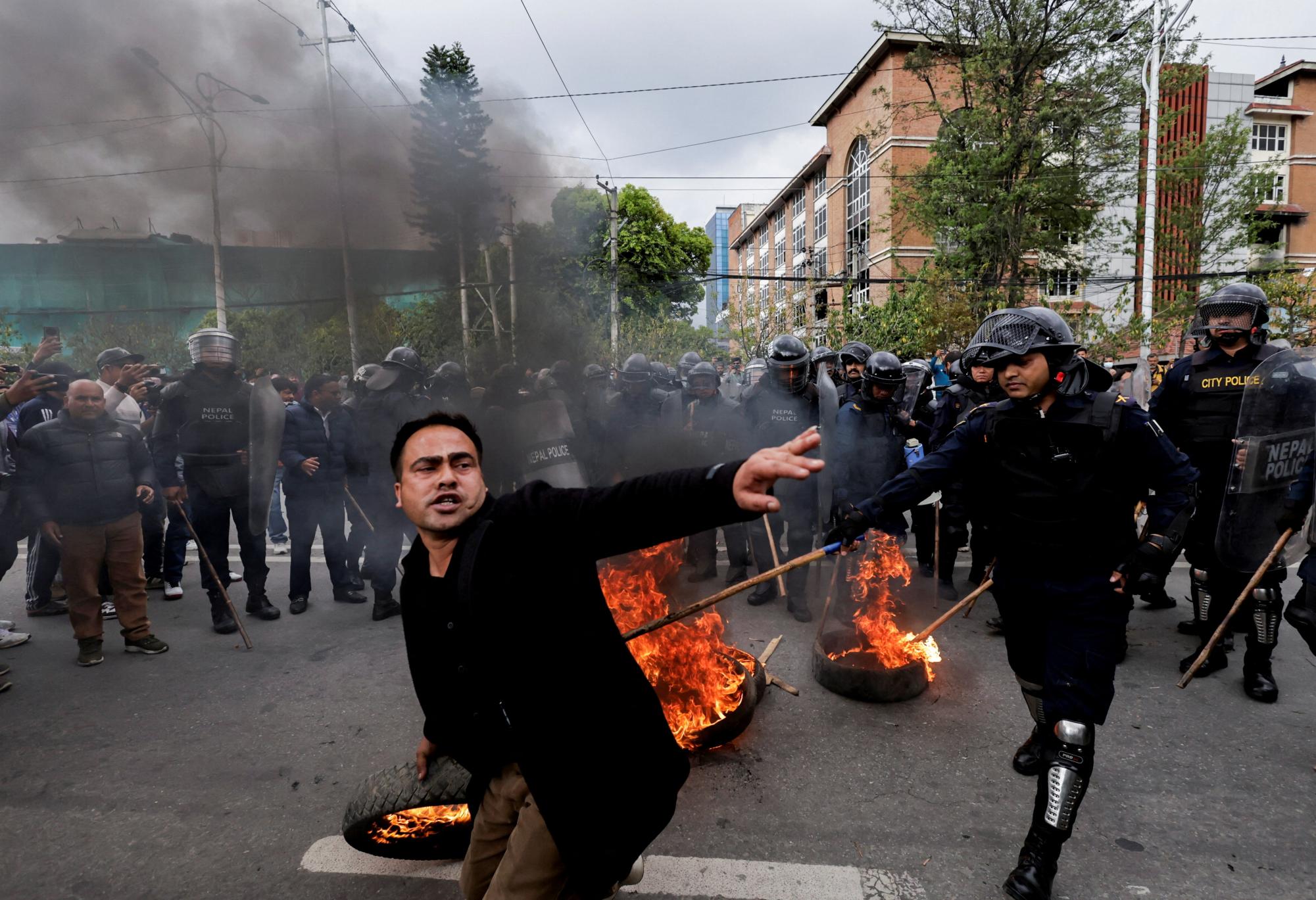 A demonstrator attempts to hurl a flaming tyre as police try to stop him during a protest following Nepal’s former Prime Minister and Chairman of the Communist Party of Nepal, K.P. Sharma Oli detention by police, who are investigating whether he was negligent in preventing dozens of deaths during the Gen Z protests, in Kathmandu, Nepal, March 28, 2026. REUTERS/Navesh Chitrakar